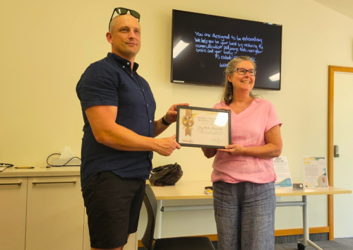A GMC Chiropractors representative presents a Hospice Whanganui Business Champions certificate to a Hospice Whanganui staff member during an in-house wellbeing presentation.